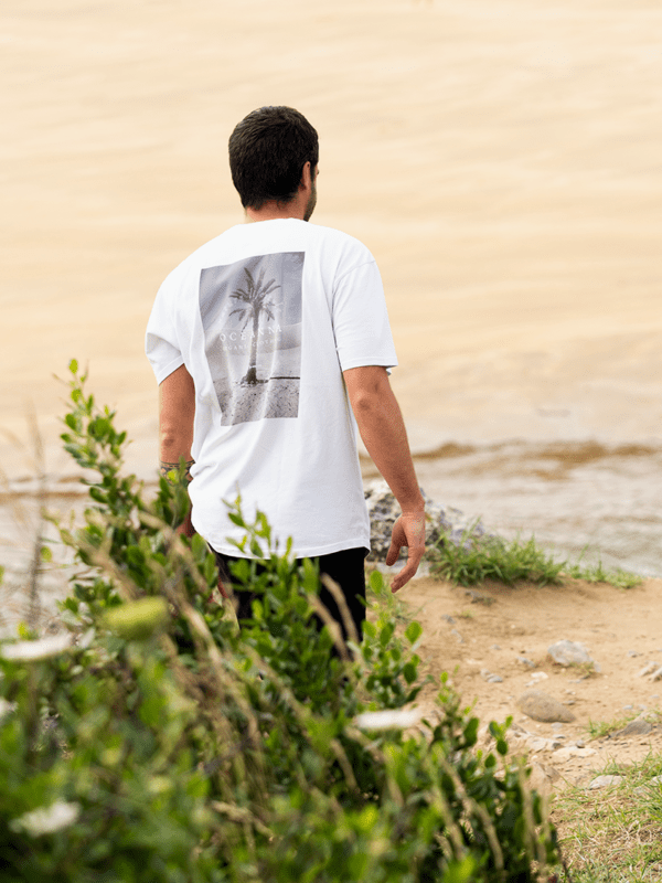 Camiseta unisex blanca "Desert Palm" de Oceanna Clothing con dibujo de palmera y logotipo de la marca.